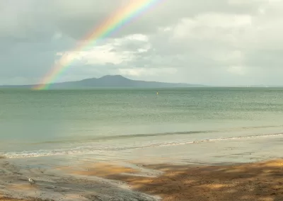 Rainbow over Hauraki Gulf and Rangitoto Island from an Auckland beach